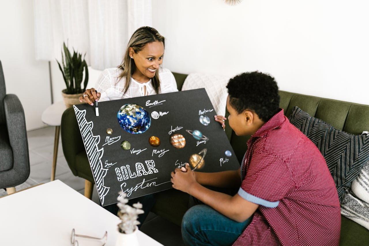 Mother and child learning about the solar system with a creative poster in a cozy living room.